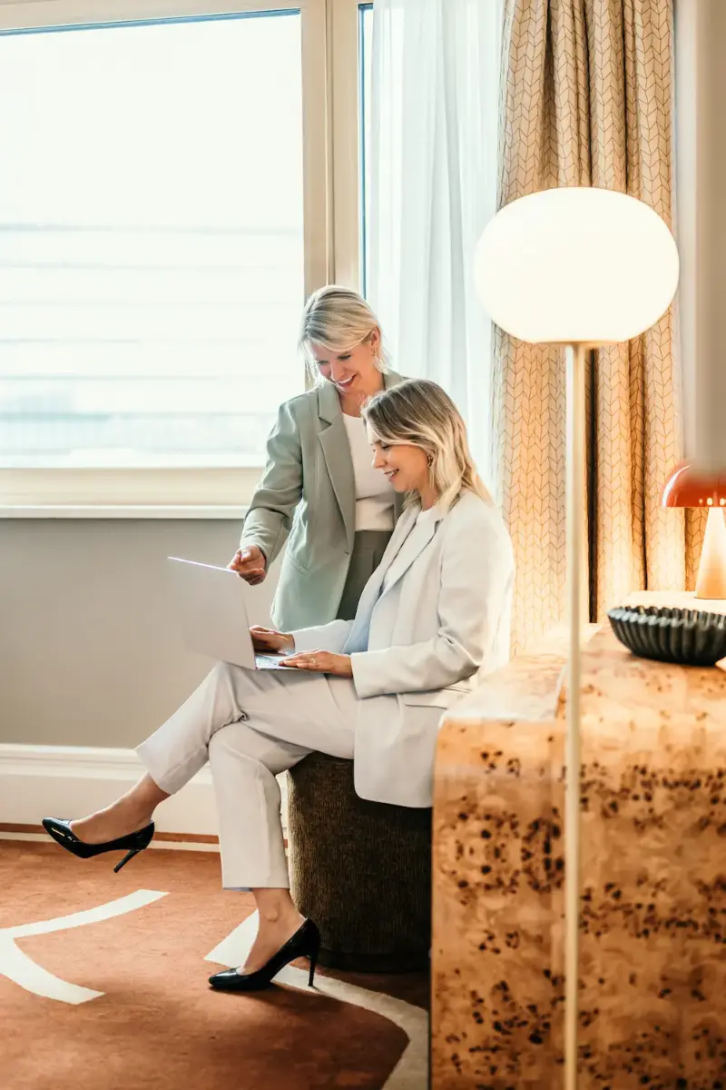 Zwei Beraterinnen vergleichen Hotelangebote am Laptop