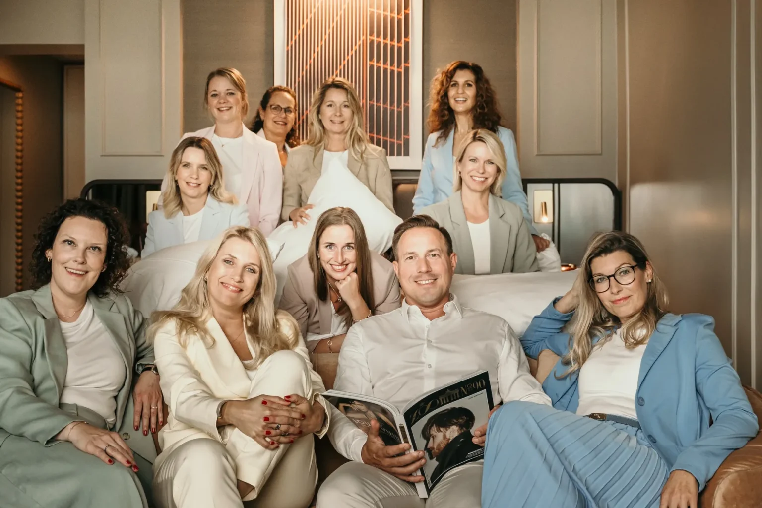 Das Team der Hotelspezialisten sitzt gemeinsam auf einem Sofa in einer Hotelsuite