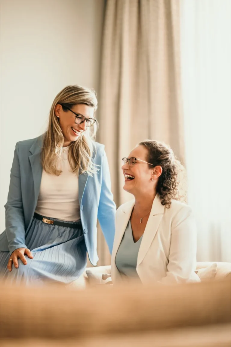 Zwei Hotelspezialistinnen lachen gemeinsam in einer Hotelsuite