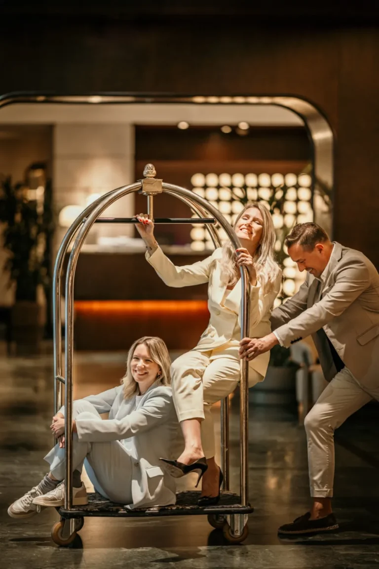 Das Team der Hotelspezialisten mit einem Gepäckwagen in einer Hotellobby