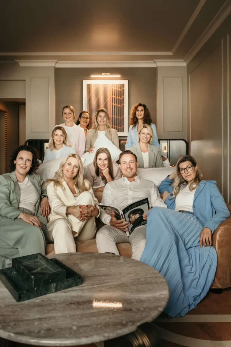 Das Team der Hotelspezialisten sitzt gemeinsam auf einem Sofa in einer Hotelsuite